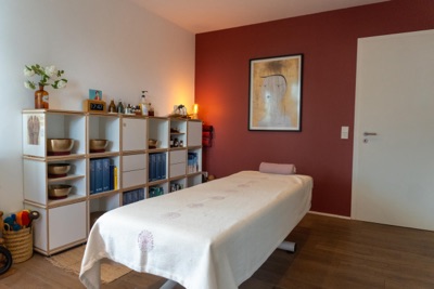 Behandlungsraum mit Liege und roter Wand